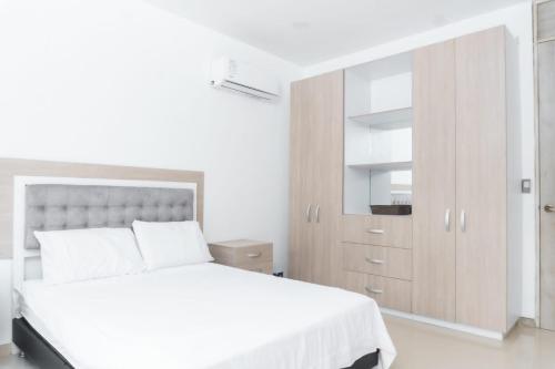 a white bedroom with a large bed and a cabinet at Casa finca con piscina in Santa Marta