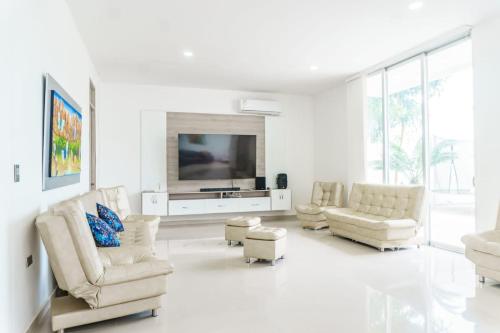 a living room with white furniture and a flat screen tv at Casa finca con piscina in Santa Marta