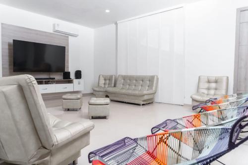 a living room with couches and a flat screen tv at Casa finca con piscina in Santa Marta