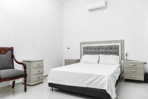 a white bedroom with a bed and a chair at Casa finca con piscina in Santa Marta
