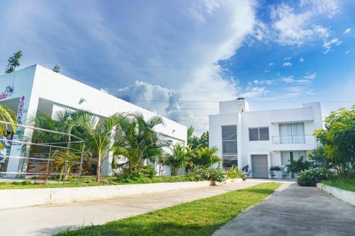 a white building with palm trees in front of it at Casa finca con piscina in Santa Marta