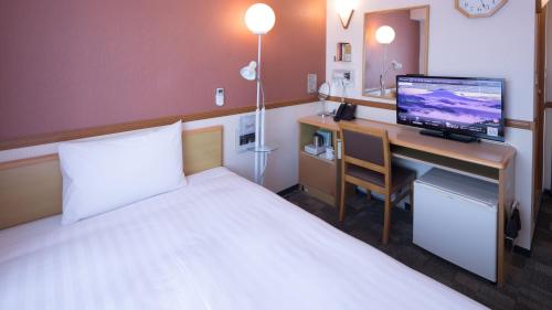 a hotel room with a bed and a desk with a computer at Toyoko Inn Shimonoseki Kaikyo yume tower Mae in Shimonoseki