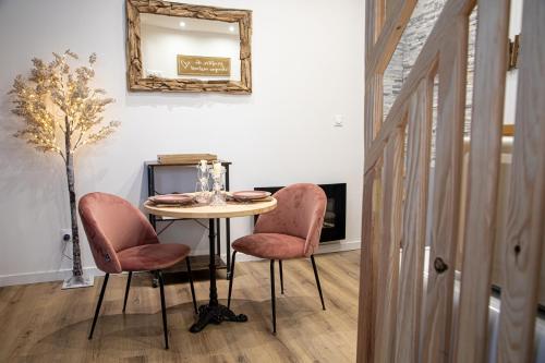 uma mesa com duas cadeiras cor-de-rosa e um espelho em Les alouettes em Caudry