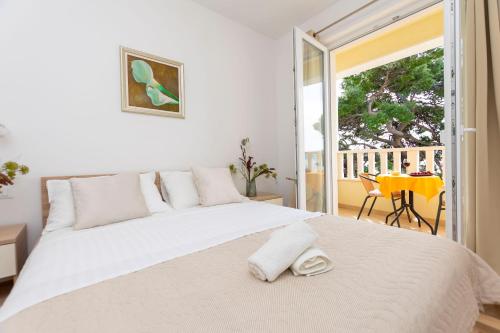 ein Schlafzimmer mit einem großen weißen Bett und einem Balkon in der Unterkunft Apartments Beach Dream in Mimice