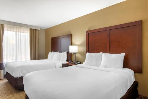 two beds in a hotel room with white sheets at Comfort Suites Locust Grove Atlanta South in Locust Grove