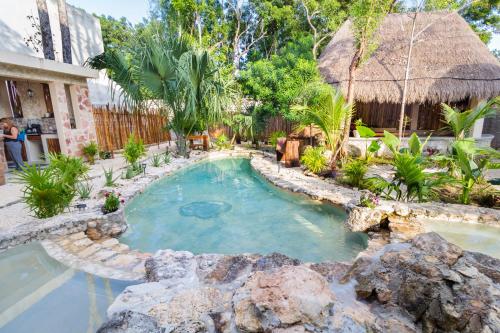 a swimming pool in a resort with a rock at Jaakbal Tulum in Tulum