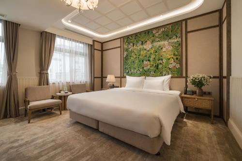 La Passion Hanoi Hotel & Spa في هانوي: غرفة نوم بسرير كبير ولوحة على الحائط