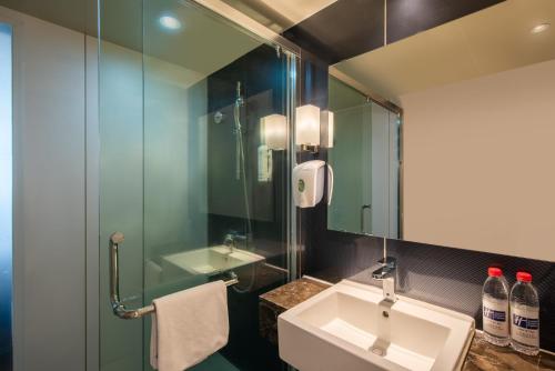 ein Bad mit einem Waschbecken und einer Glasdusche in der Unterkunft Holiday Inn Express Changbaishan, an IHG Hotel in Fusong