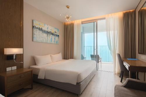 a bedroom with a bed and a desk and a window at PANORAMA Condotel by HLG in Nha Trang