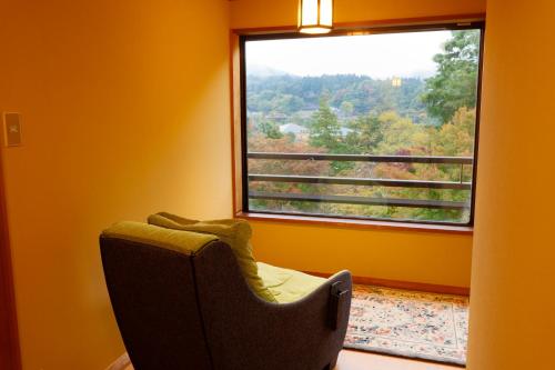 una silla frente a una ventana con vistas en Nikko Hoshino Yado en Nikko