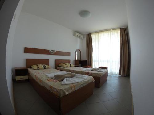 a hotel room with two beds and a window at Hotel Filland in Sozopol