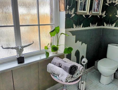 a bathroom with a toilet and a window and towels at 4 bedroom period Townhouse in the heart of Hebden in Hebden Bridge