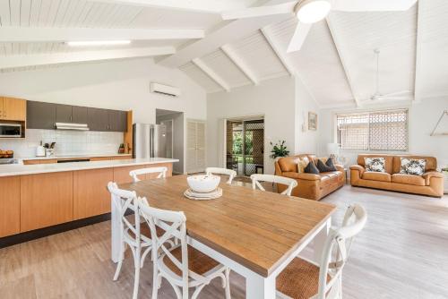 Una cocina y una sala de estar con una mesa y sillas de madera. en Seashells - Popular Beach House, en Yamba
