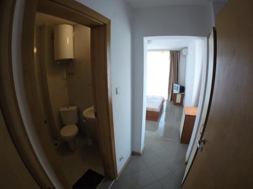 a bathroom with a toilet and a room with a bed at Hotel Filland in Sozopol