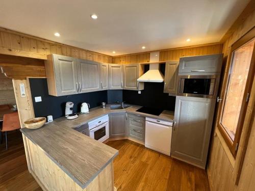 une cuisine avec des armoires en bois et un comptoir dans l'établissement Joli chalet au calme avec poêle à bois, 4 chambres et cuisine équipée - FR-1-593-84, aux Angles