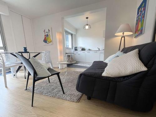 un salon avec un canapé noir et une table dans l'établissement Appartement rénové à Bénodet, plage à 100m, terrasse, parking, proche thalasso et restaurants - FR-1-481-136, à Bénodet