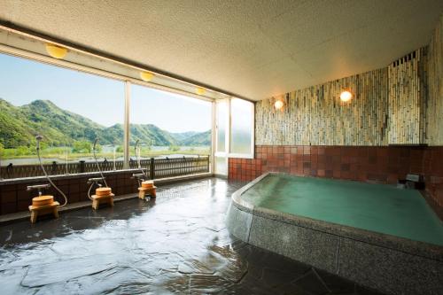 a swimming pool in a room with a large window at Oyado Seri in Toyooka