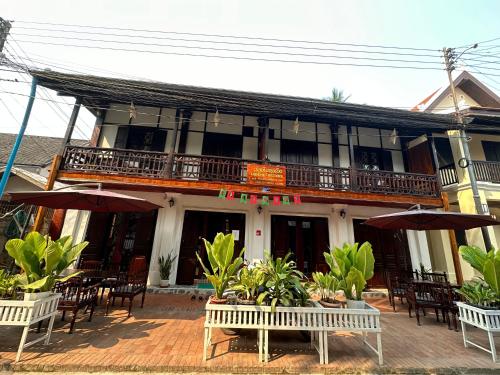 a building with tables and chairs in front of it at Khounphet Heritage House in Luang Prabang