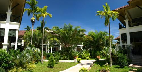 a group of palm trees in front of a building at Baan Khaolak Beach Resort in Khao Lak
