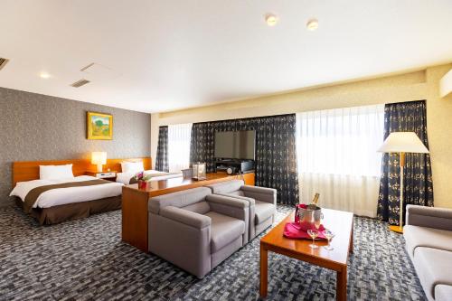 a hotel room with a bed and a living room at Yamagata Grand Hotel in Yamagata