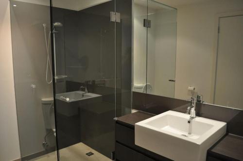 a bathroom with a sink and a glass shower at Heart of Torquay - Whitewater Apartment - Torquay in Torquay