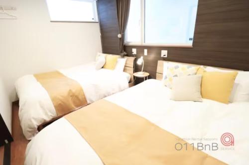 a bedroom with two beds and a window at YI HOUSE MAX 8people 2BR 1 minute walk from tram station in Sapporo