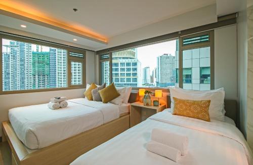 2 łóżka w pokoju z dużymi oknami w obiekcie The Mini Suites Eton Tower Makati w mieście Manila