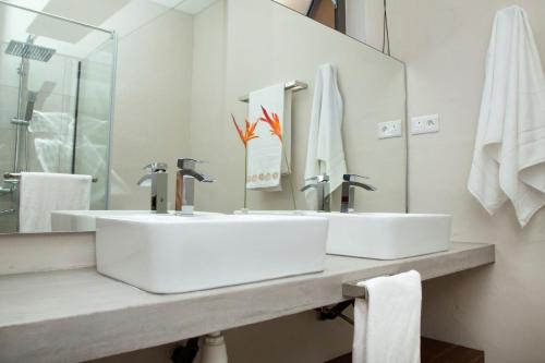 a white bathroom with two sinks and a mirror at Les 2 canons in Flic-en-Flac