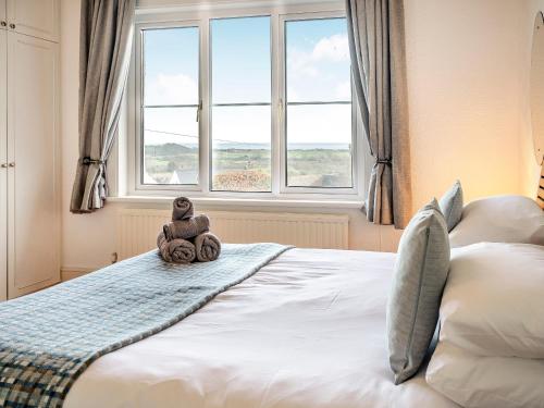 a teddy bear sitting on a bed in front of a window at Innishkea in Tenby