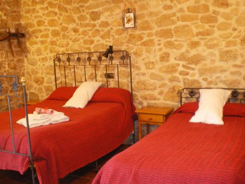 a bedroom with two beds with red sheets at Masia Del Aragones in Peñarroya de Tastavins
