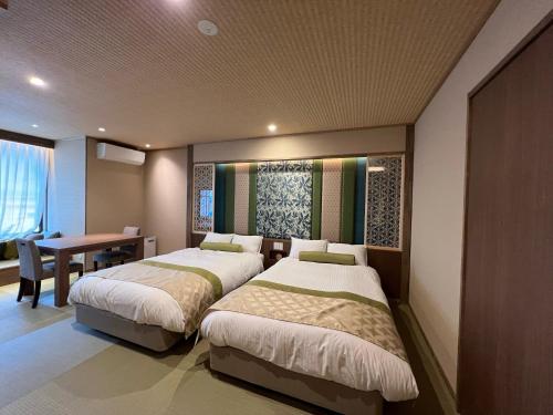 1 dormitorio con 2 camas, mesa y escritorio en Marukyoo, en Nikko