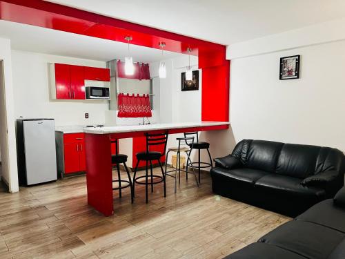 una cocina con armarios rojos y un bar con taburetes en Hotel Halley en León