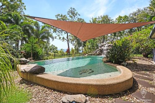 a pool in a yard with a umbrella over it at Heavens Gates - Privacy Near Ellis Beach in Wangetti