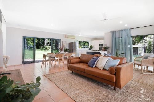 a living room with a brown couch and a kitchen at Heavens Gates - Privacy Near Ellis Beach in Wangetti