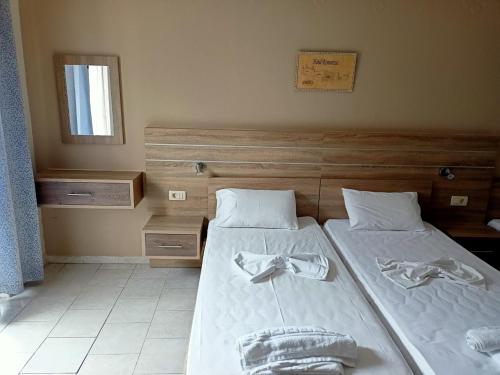 a bedroom with two beds with white sheets and a mirror at ROMANTZA apartments in Agia Marina Nea Kydonias