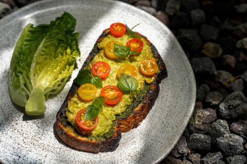 Un trozo de pan tostado con tomate y lechuga en un plato. en Jati Cottage, en Ubud
