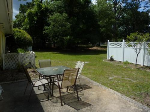a patio with a table and chairs in a yard at LYONS DEN - 3 Bedroom Home home in Jekyll Island