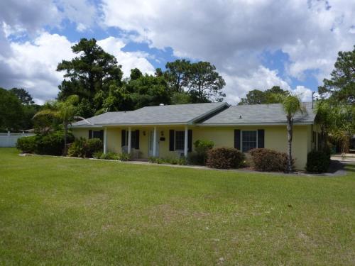 a yellow house with a lawn in front of it at LYONS DEN - 3 Bedroom Home home in Jekyll Island