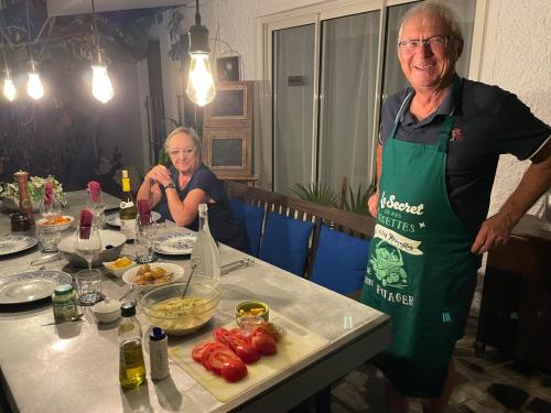 a man in an apron standing next to a table with food at Bellevue Tamarin in Tamarin