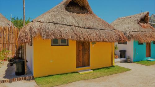 a small yellow house with a thatched roof at Casa Frida in Chelem