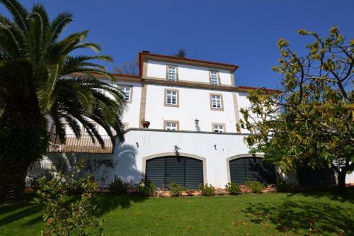 a white house with a palm tree in front of it at Quinta de Malta in Durrães