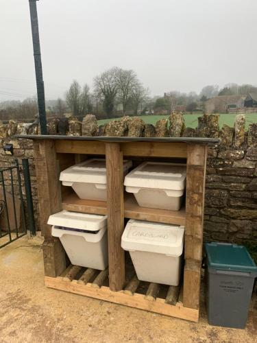a wooden shelf with toilets in front of a stone wall at The Milking Sheds in Tytherington