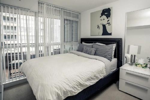 a bedroom with a large bed and a large window at 1200+sqft Luxury Corner Suite in Toronto