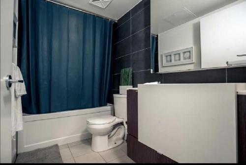 a bathroom with a toilet and a blue shower curtain at 1200+sqft Luxury Corner Suite in Toronto