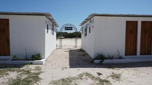 two white buildings with wooden doors and a gate at Casa Frida in Chelem