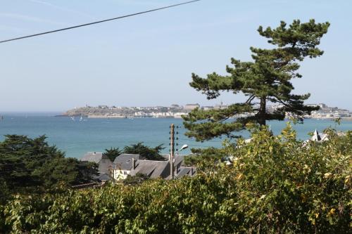 a view of the ocean and a house with a tree at Chambres d'hôtes Christa in Saint-Pair-sur-Mer