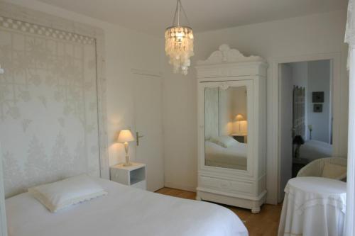 ein weißes Schlafzimmer mit einem weißen Bett und einem Kronleuchter in der Unterkunft Chambres d'hôtes Christa in Saint-Pair-sur-Mer