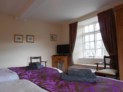 Un dormitorio con una cama con sábanas moradas y una ventana en The Granary, Old Corn Mill, Yorkshire Dales, en West Burton