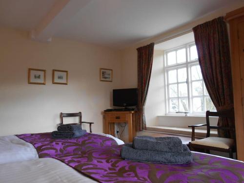 a bedroom with a bed with purple sheets and a window at The Granary, Old Corn Mill, Yorkshire Dales in West Burton