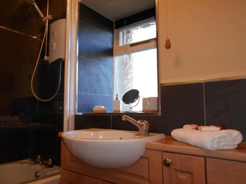 a bathroom with a white sink and a window at The Granary, Old Corn Mill, Yorkshire Dales in West Burton